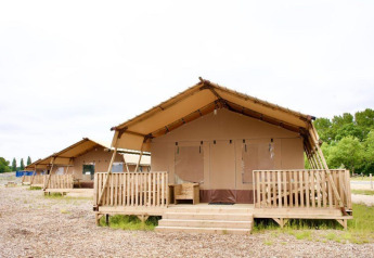Großes Foto von Lodges mit Holzterrassen in natürlicher Umgebung und grünen Bäumen im Hintergrund.