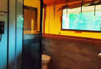 Badkamer in Glampingtent Kompact bij Molengroet, Nederland, met douche, toilet, wasbak en groot raam.