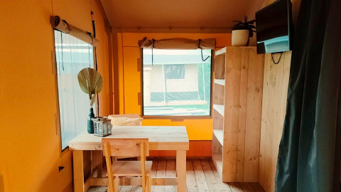 Intérieur de la Glampingtent Kompact à Molengroet, Pays-Bas, avec meubles en bois et fenêtre.