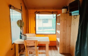 Interior of Glampingtent Kompact at Molengroet in the Netherlands, showing wooden furniture and window.