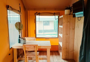 Interior of Glampingtent Kompact at Molengroet in the Netherlands, showing wooden furniture and window.