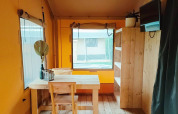 Interieur van Glampingtent Kompact bij Molengroet in Nederland, met houten meubels en raam.