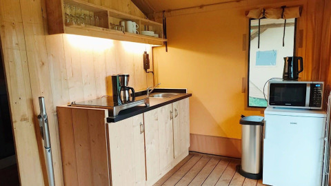 Køkkenområde i Glampingtent Kompact ved Molengroet, Holland, med vask, kaffemaskine og mikrobølgeovn.
