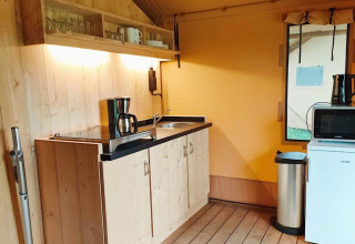 Køkkenområde i Glampingtent Kompact ved Molengroet, Holland, med vask, kaffemaskine og mikrobølgeovn.