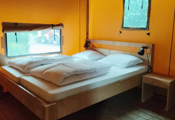 Interior view of Glampingtent Kompact at Molengroet, Netherlands, showing a wooden double bed and nightstand.