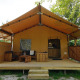 Glampingtent Sunshine-lodgen med træterrasse og siddeområde i hyggelige, grønne omgivelser.