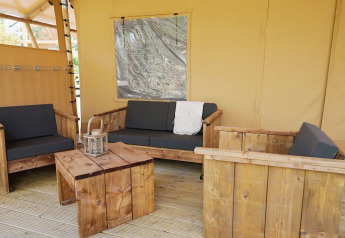 Outdoor seating at Glampingtent Sunshine in Molengroet, Netherlands, with wooden furniture and cushions.