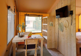 Interno luminoso di una Glampingtent Sunshine a Molengroet nei Paesi Bassi, con mobili in legno e TV.