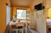 Helles Interieur eines Glampingtent Sunshine bei Molengroet in den Niederlanden, mit Holzmöbeln und TV.