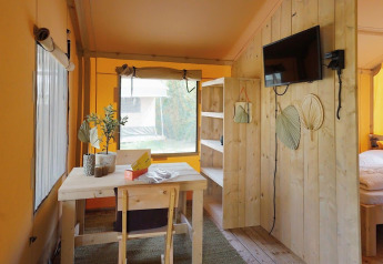 Helles Interieur eines Glampingtent Sunshine bei Molengroet in den Niederlanden, mit Holzmöbeln und TV.