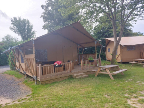 Glampingtent Sunshine bij Molengroet in Nederland, met houten veranda en picknicktafels op het gras.