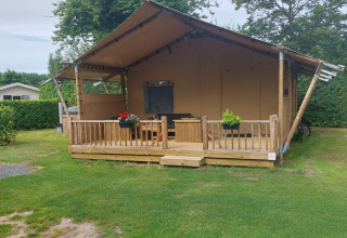 Glamping tent Sunshine at Molengroet in the Netherlands, featuring a wooden porch and grassy lawn.
