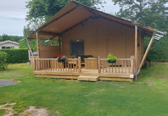 Glamping tent Sunshine at Molengroet in the Netherlands, featuring a wooden porch and grassy lawn.
