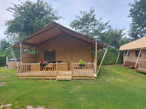 Glampingtent Sunshine à Molengroet aux Pays-Bas, vue extérieure avec terrasse en bois et pelouse.