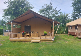 Glampingtent Sunshine at Molengroet in the Netherlands, with wooden deck and lawn in front view.
