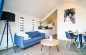 Moderne Beach House lodge aan Bad Hulckesteijn met blauwe zetel, eetruimte en opvallende kunst aan de muur.
