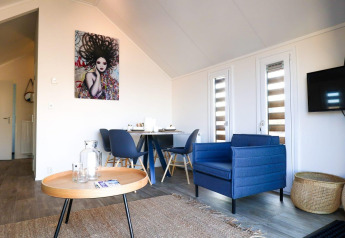 Moderne lodge met een blauwe zetel, eetruimte, opvallende wanddecoratie en houten bijzettafeltje.