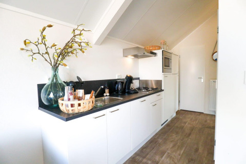 Moderne Küchenzeile im Beach House von Bad Hulckesteijn, Niederlande, mit Deko und Holzfußboden.