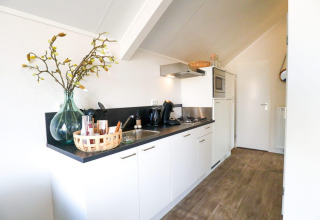 Petite cuisine moderne au Beach House de Bad Hulckesteijn, Pays-Bas, avec sol en bois et déco élégante.