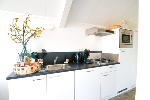 Cuisine lumineuse et moderne dans un lodge, avec placards blancs, gazinière, micro-ondes et déco.