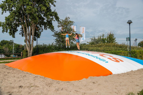 Kinder springen auf einem großen Luftkissen-Spielplatz bei einer Glamping-Unterkunft im Freien.