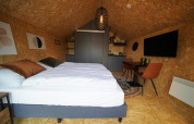 Vista interior del lodge Solo Retreat en Bad Hulckesteijn, Países Bajos, con cama y decoración moderna.