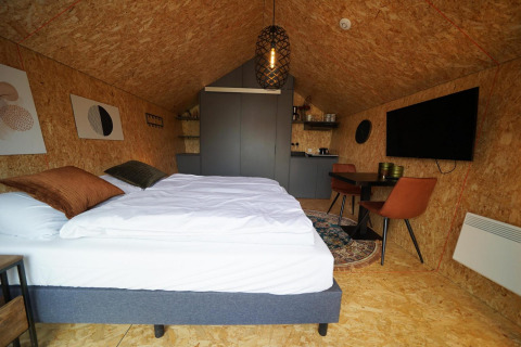 Indvendig udsigt over Solo Retreat-lodgen på Bad Hulckesteijn i Holland med moderne interiør og dobbeltseng.