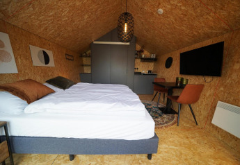 Indvendig udsigt over Solo Retreat-lodgen på Bad Hulckesteijn i Holland med moderne interiør og dobbeltseng.