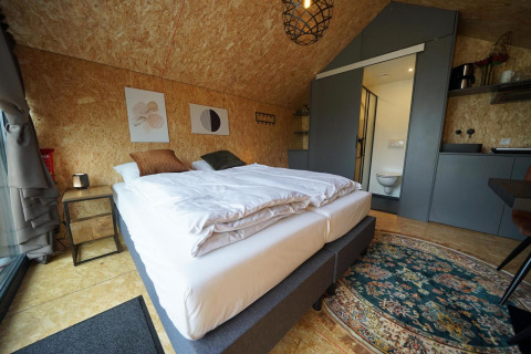 Modernes Lodge-Zimmer mit Doppelbett, Bad und Küchenzeile im Solo Retreat, Bad Hulckesteijn, Niederlande.