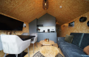 Interior moderno de cabaña con sofá, mesa de comedor, sillas y cocina en Solo Retreat, Bad Hulckesteijn, Países Bajos.