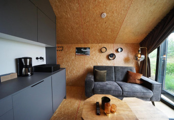 Interno moderno della lodge Solo Retreat a Bad Hulckesteijn, Paesi Bassi, con divano grigio e cucina.