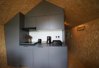 Strakke grijze kitchenette bij Solo Retreat te Bad Hulckesteijn, Nederland, met moderne apparatuur.