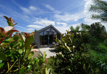 Moderne Solo Retreat lodge bij Bad Hulckesteijn in Nederland, omgeven door groen en een blauwe lucht.