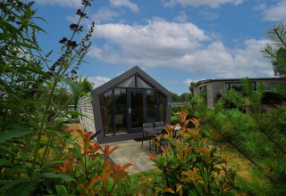 Cabaña Solo Retreat en Bad Hulckesteijn, Países Bajos, diseño moderno y rodeada de vegetación y cielo azul.