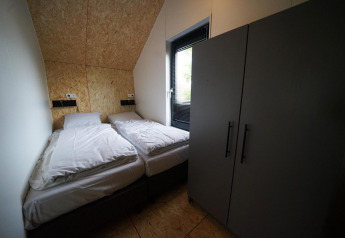 Zimmer im Solo Retreat im Bad Hulckesteijn, Niederlande, mit zwei Einzelbetten und Kleiderschrank.
