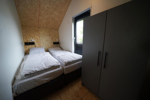 Chambre du Solo Retreat à Bad Hulckesteijn, Pays-Bas, avec deux lits simples et une grande armoire.