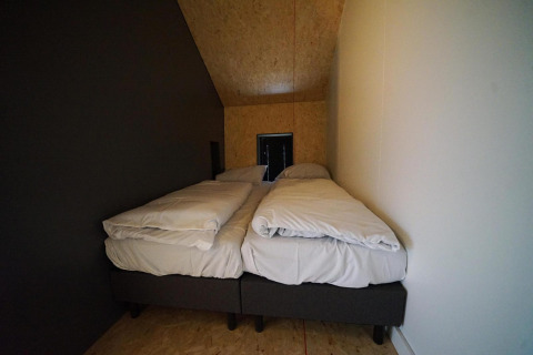 Twee eenpersoonsbedden met wit beddengoed in een smalle kamer bij Solo Retreat, Bad Hulckesteijn, Nederland.
