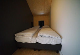 Dos camas individuales con ropa de cama blanca en una habitación pequeña en Solo Retreat, Bad Hulckesteijn, Países Bajos.
