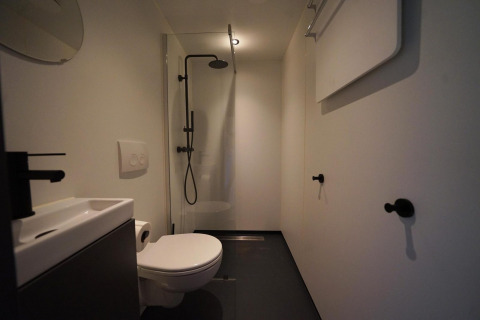 Moderne badkamer bij Solo Retreat te Bad Hulckesteijn in Nederland, met douche, toilet en wastafel.
