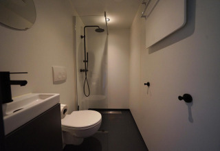 Moderne badkamer bij Solo Retreat te Bad Hulckesteijn in Nederland, met douche, toilet en wastafel.