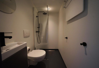 Moderne badeværelse på Solo Retreat ved Bad Hulckesteijn i Holland med toilet, bruser og vask.
