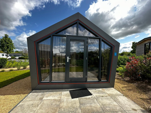 Moderne Solo Retreat lodge aan Bad Hulckesteijn in Nederland met glazen voorkant en tuin.