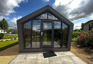 Moderne Solo Retreat lodge aan Bad Hulckesteijn in Nederland met glazen voorkant en tuin.