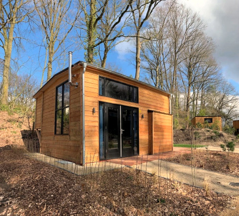 Tiny house en bois moderne à Bad Hulckesteijn, Pays-Bas, entourée d’arbres dans la forêt.