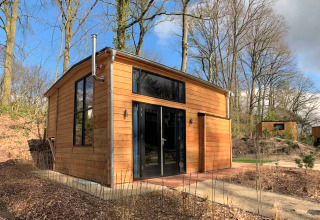 Tiny house en bois moderne à Bad Hulckesteijn, Pays-Bas, entourée d’arbres dans la forêt.