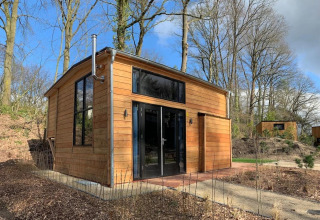 Tiny house di legno a Bad Hulckesteijn, Paesi Bassi, immersa tra alberi in un ambiente naturale.