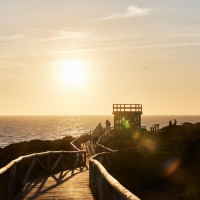 Atardecer en la pasarela de madera junto al mar cerca de Conil de la Frontera, Andalucía, España.