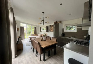 Modernes Wohnzimmer und Küche in einer L-Pavilion-Lodge im Poort van Zeeland, Niederlande, mit Esstisch.