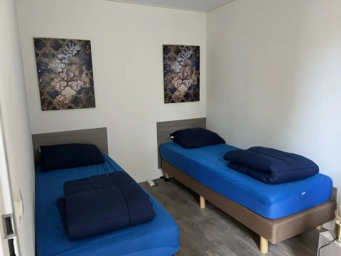 Slaapkamer met twee eenpersoonsbedden, blauw beddengoed en muurkunst in L-Pavilion, Poort van Zeeland.