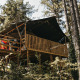 Safari-telt lodge med sanitære faciliteter, beliggende i en skov med sollys og grønne træer omkring.